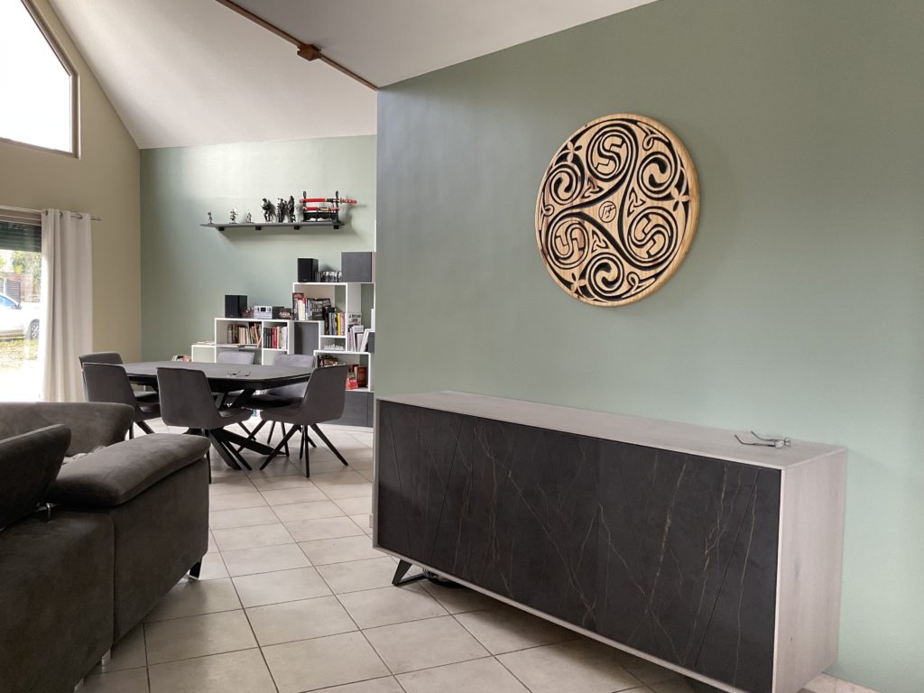 Pan de mur vert kaki clair mettant en valeur le triskel personnalisé en bois - Concept Déco LV - Décoratrice d'intérieur à Caen